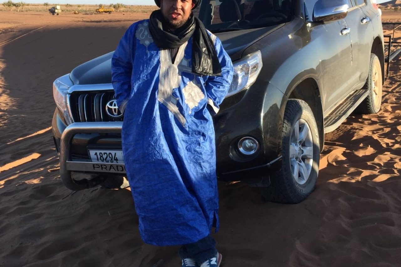 A 4x4 on a desert piste with the Erg Chebbi dunes on the horizon