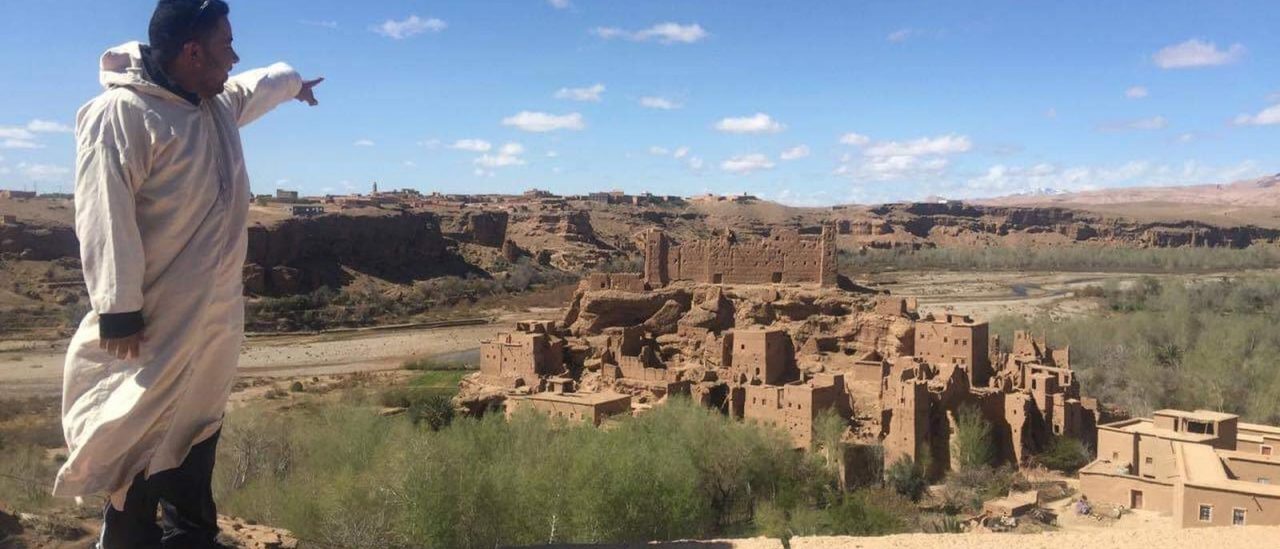 Un guide et des voyageurs contemplant une vallée de kasbahs dans le sud du Maroc