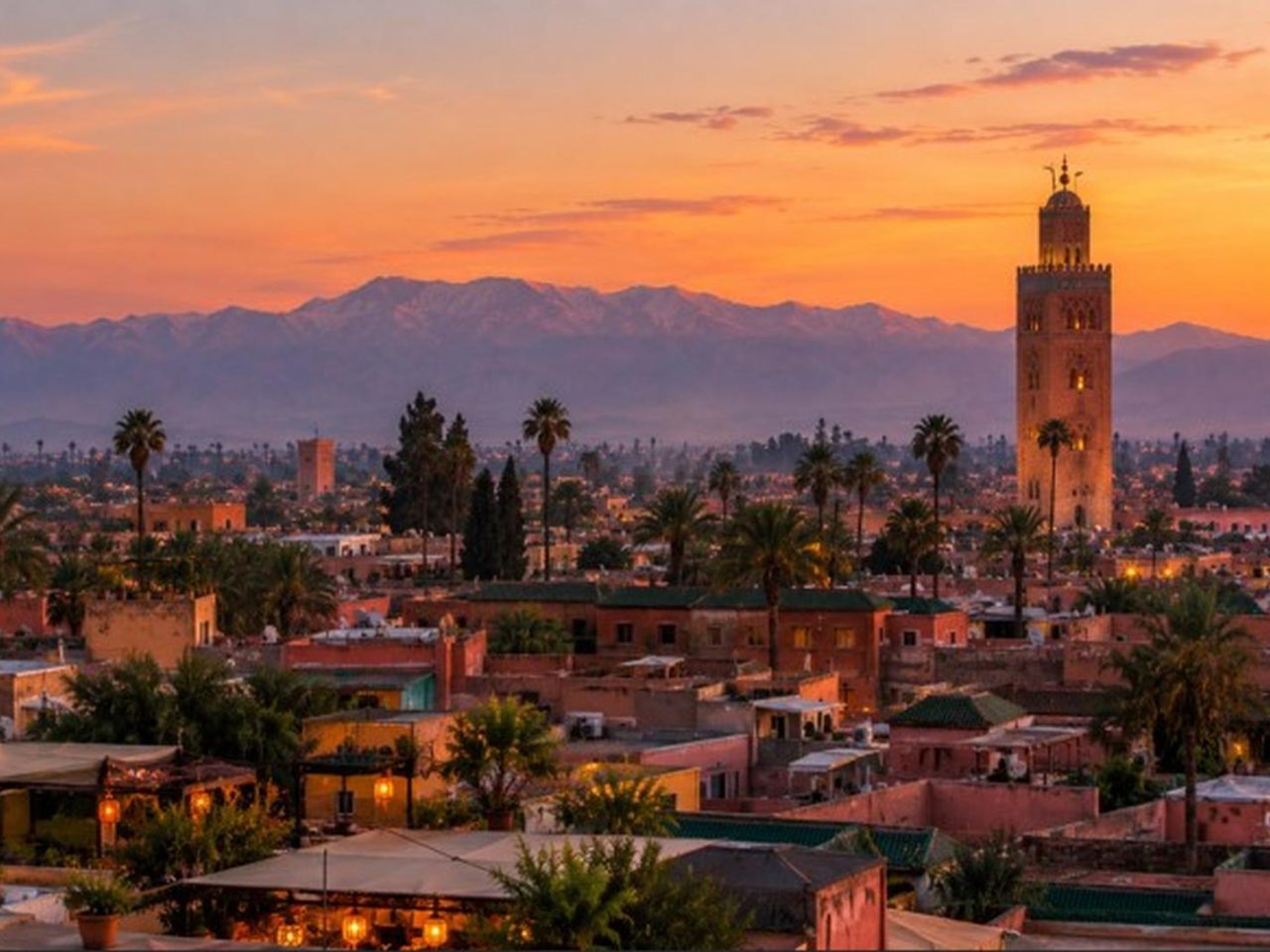 Toits et minaret de la médina de Marrakech au crépuscule, l'Atlas en arrière-plan