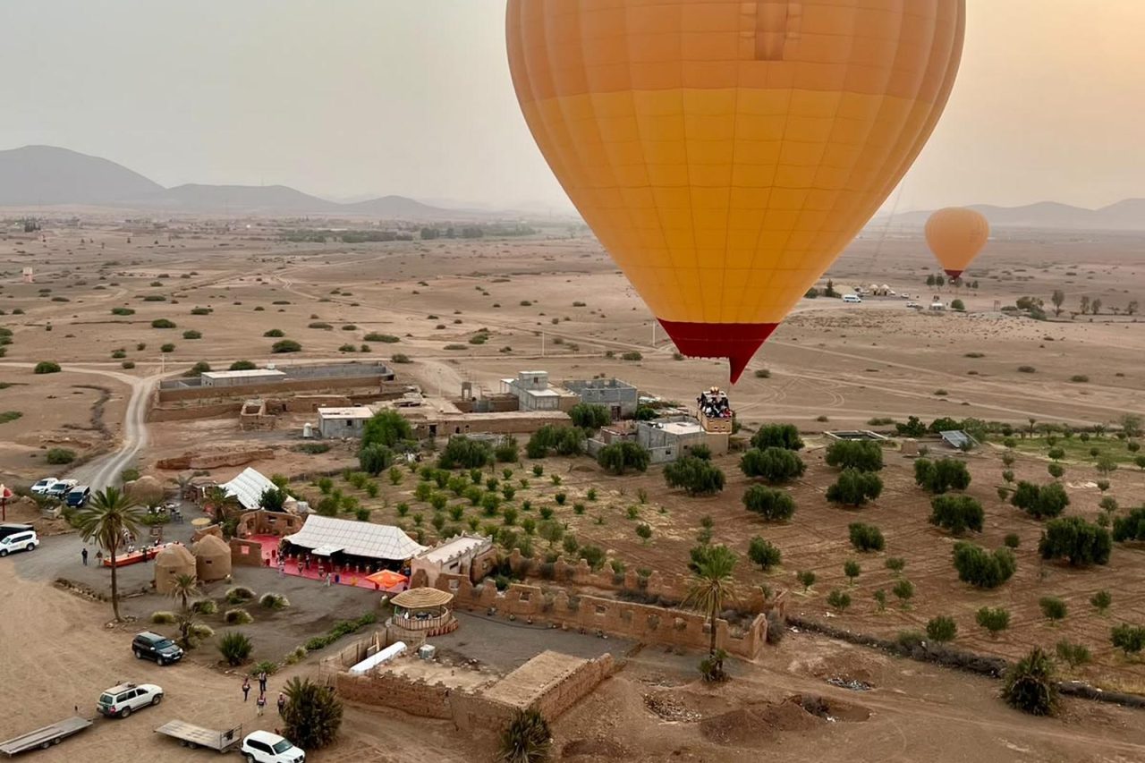 Hot air balloon rising at sunrise over the plains north of Marrakech with the Atlas Mountains behind