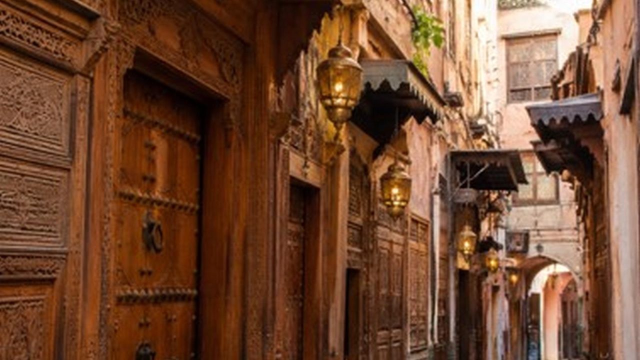 Ruelle de la médina de Fès bordée de portes en bois sculpté et de lanternes en laiton